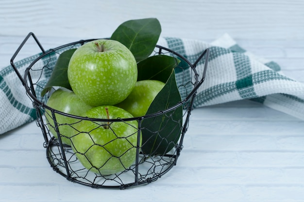 Green apples with leaves in the metallic black basket placed on white background . High quality photo