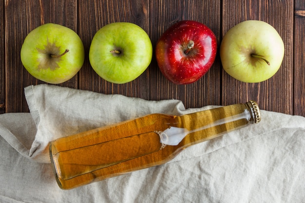 Foto gratuita mele verdi con una rossa e vista superiore del succo di mele su un panno e su un fondo di legno