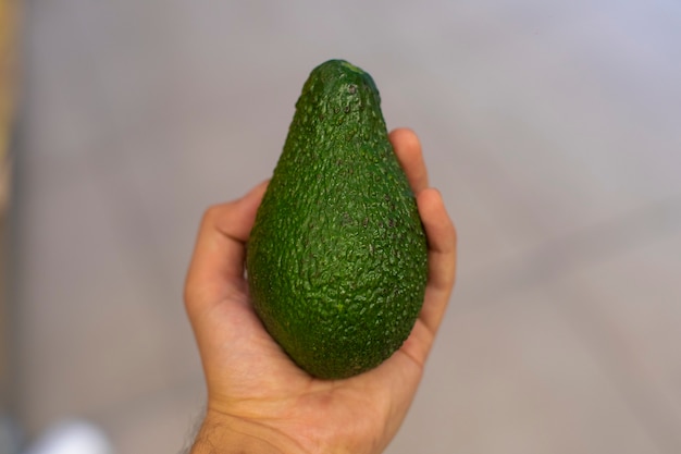 A green avocado in the hand of a person