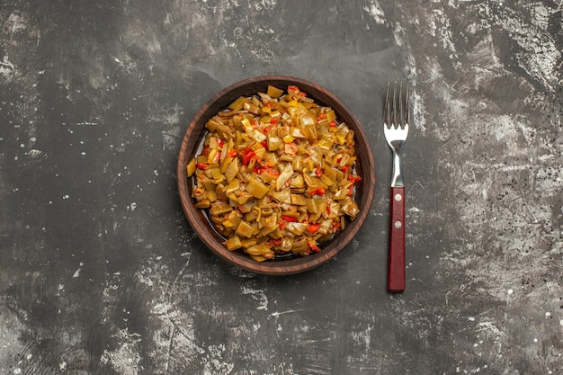 Fagiolini fagiolini e pomodori nella ciotola di legno accanto alla forchetta sul tavolo scuro