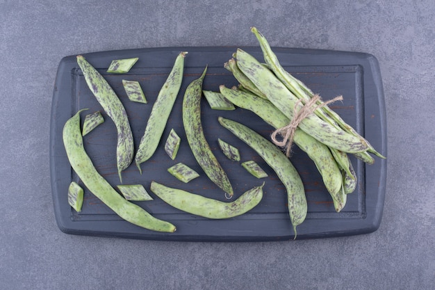 Free photo green beans inside a container or platter on concrete background.