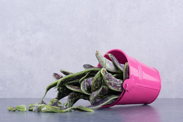 Green beans inside a container or platter on concrete background.