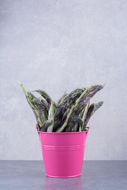 Green beans isolated in a container on blue surface