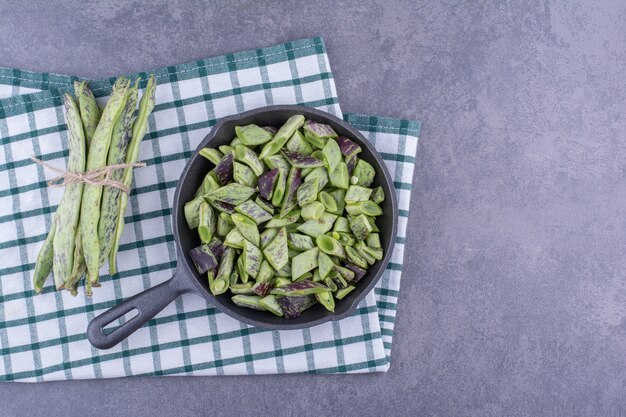 Green beans isolated in a wooden tray on blue surface