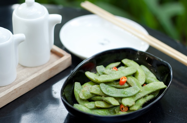 Green beans with red chilli in black ceramic bowl
