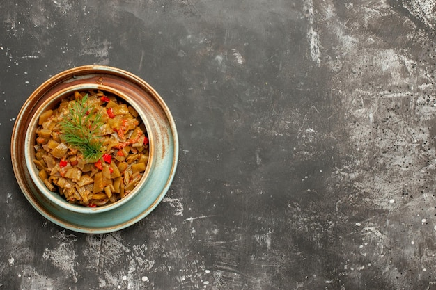 어두운 탁자의 왼쪽에 토마토가 있는 식욕을 돋우는 녹색 콩의 토마토 그릇