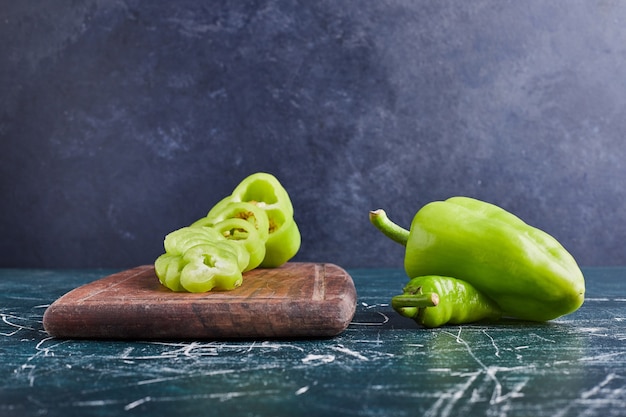 Green bell pepper slices on a wooden board.