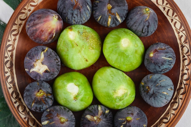 Free photo green and black figs on a ceramic plate, close up