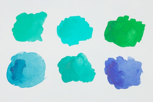 Green, blue and aquamarine blots of paints on white paper