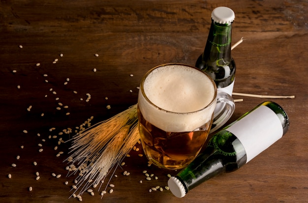 Зеленые бутылки пива с бокалом пива на деревянный стол