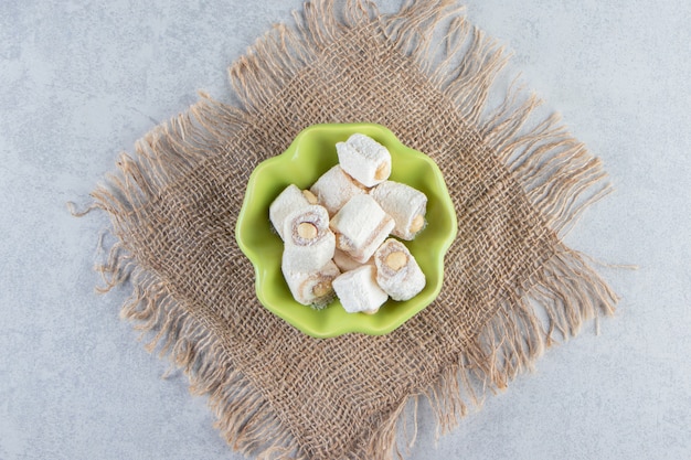 Бесплатное фото Зеленая миска вкусных угощений с орехами на камне.