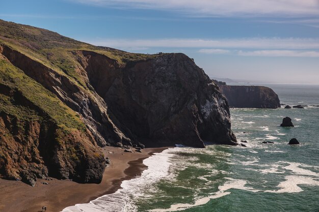 Green and brown mountain beside sea during daytime