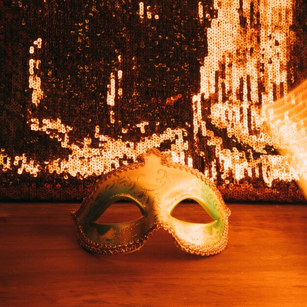 황금 반짝이 장식 조각으로 나무 책상에 녹색 카니발 마스크