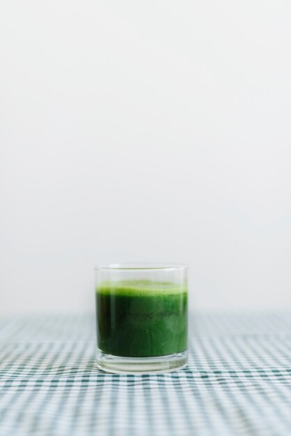 Green celery smoothie in glass on desk