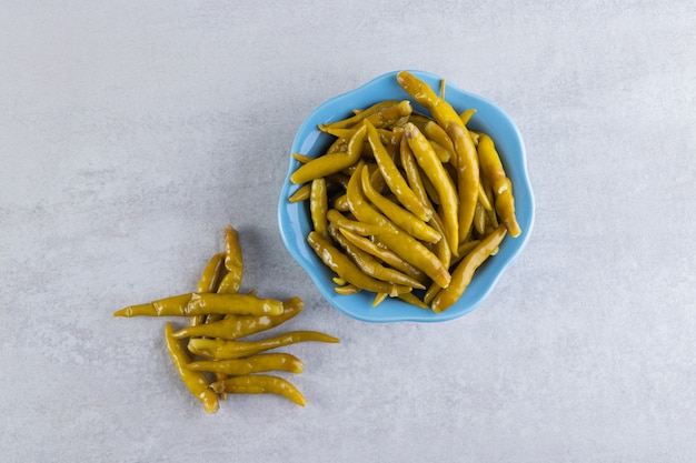 Green chili pepper pickled placed on a stone surface. 