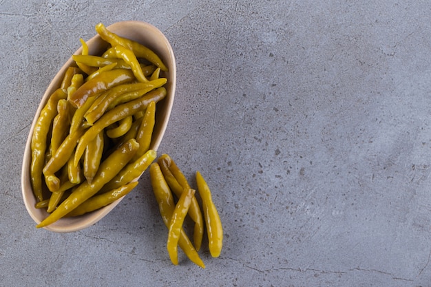 Green chili pepper pickled placed on a stone surface.