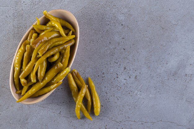 Green chili pepper pickled placed on a stone surface.