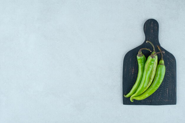 Green chili peppers on dark board.