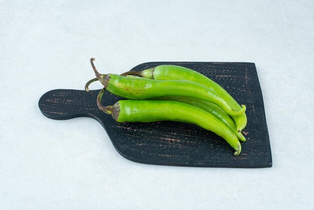 Green chili peppers on dark board.