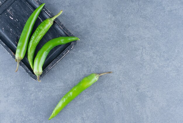 Green chili peppers on wooden board.