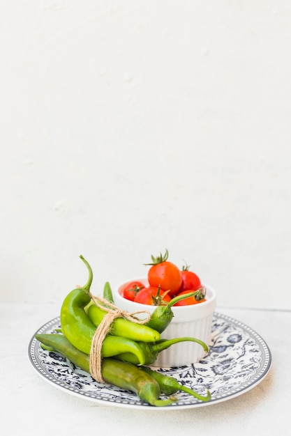 녹색 고추와 흰색 배경에 대해 세라믹 접시에 빨간 토마토의 그릇