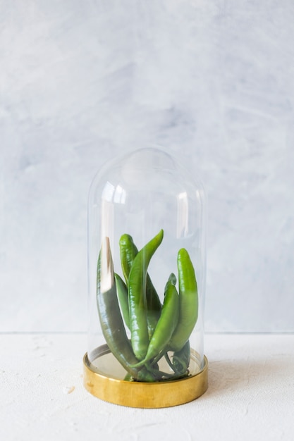 Green chilies in the glass container against texture background