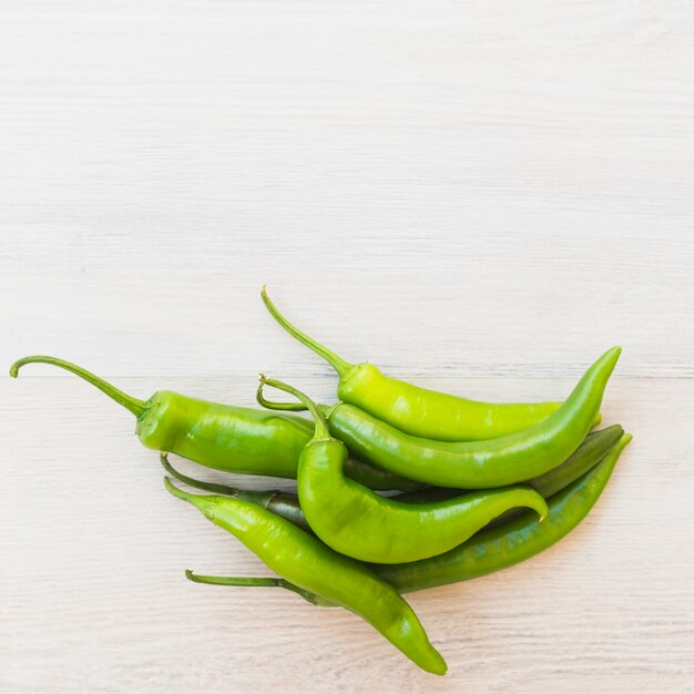 Green chilies on wooden background