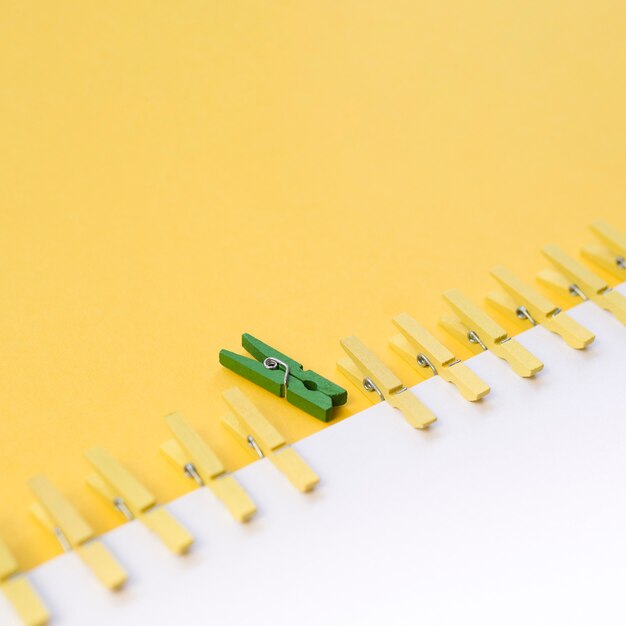 Green clothespin surrounded by yellow ones