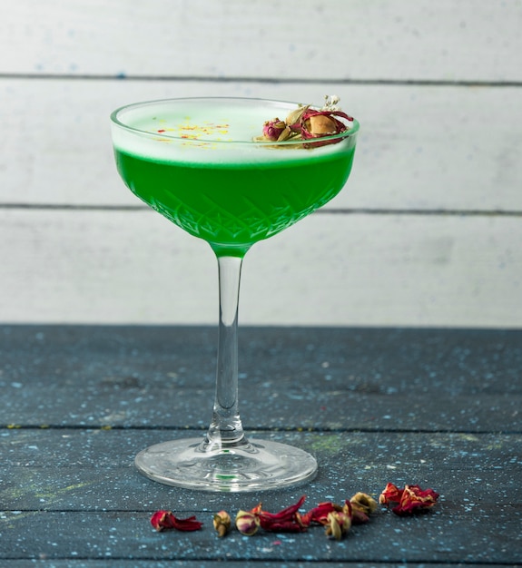 Green cocktail in crystal glass garnished with dried rose buds