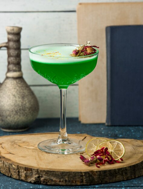 green cocktail garnished with dried rose buds in crystal glass