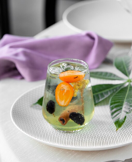 green cocktail with citrus fruits and cinnamon stick.