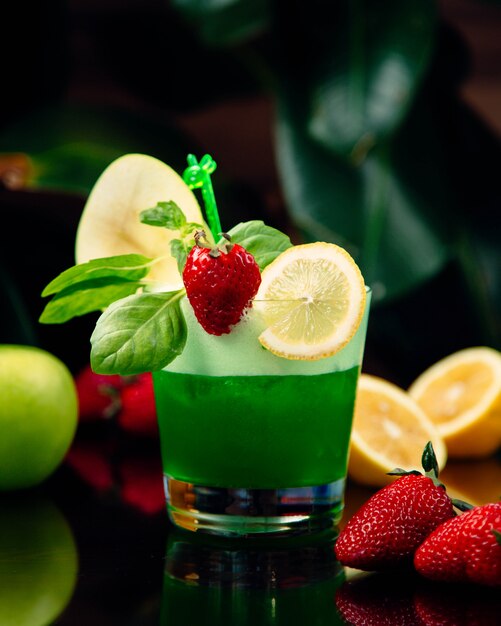 Green cocktail with lemon slices and strawberry