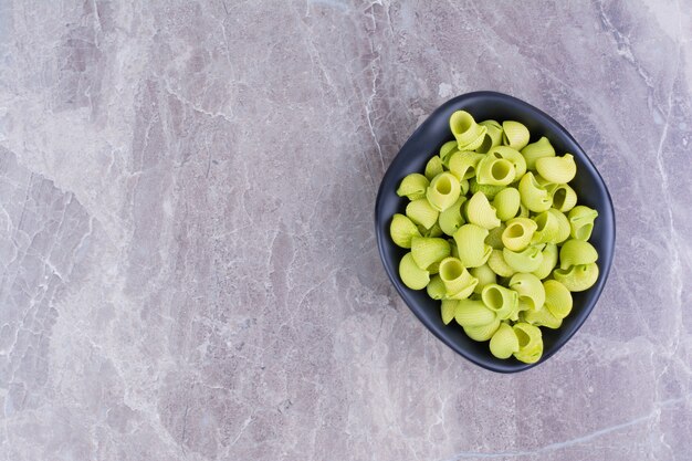 Green color homemade pastas in a plate on the marble. 