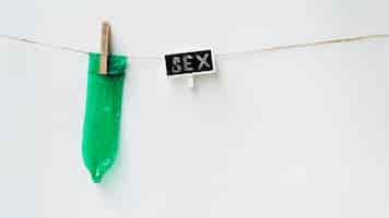 Free photo green condom on clothesline with white background