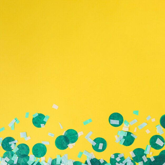 Green confetti on yellow background with copy space