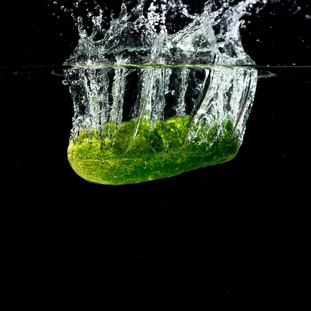 Зеленый огурец брызгает в чистую воду