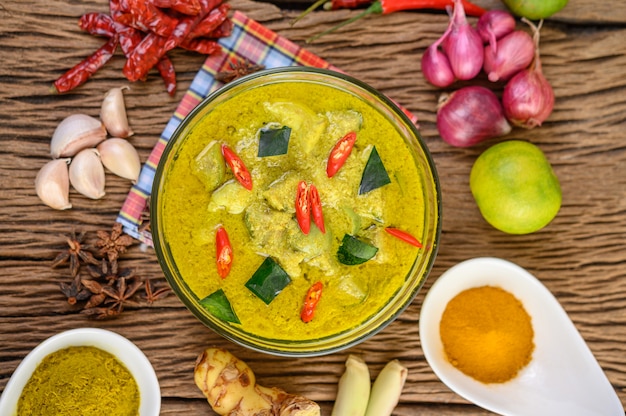 Foto gratuita curry verde in una ciotola e spezie sulla tavola di legno.