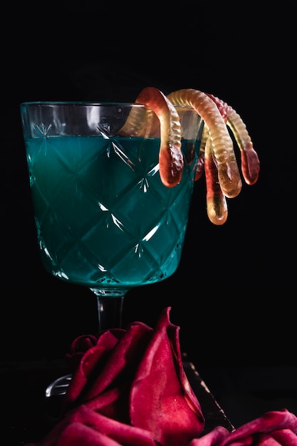 Foto gratuita bevanda verde con vermi di gelatina e rose