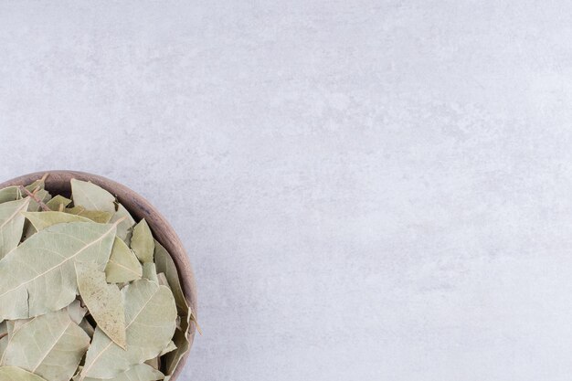 Green dry bay leaves in a cup on concrete background. High quality photo