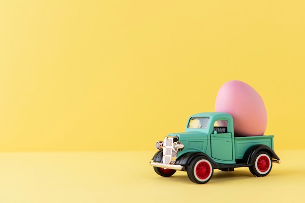 Automobile verde di pasqua con l'uovo rosa e lo spazio della copia