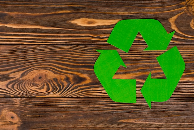 Green eco recycle logo on wooden background 