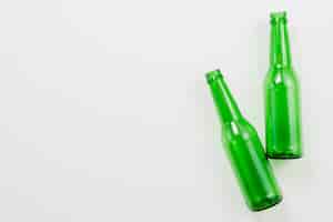 Бесплатное фото Зеленые пустые бутылки на белом фоне