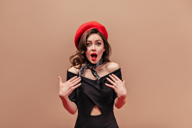 Green-eyed girl with red lips in amazement looking at camera. Portrait of lady in silk scarf around her neck.