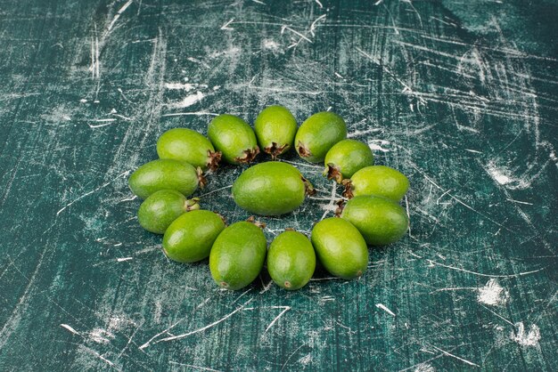 Green feijoa fruits on marble surface.