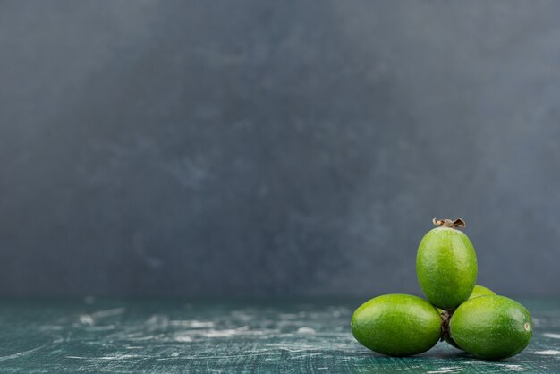 Green feijoa fruits on marble surface.