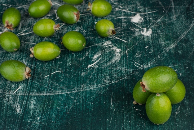 Green feijoa fruits on marble surface.