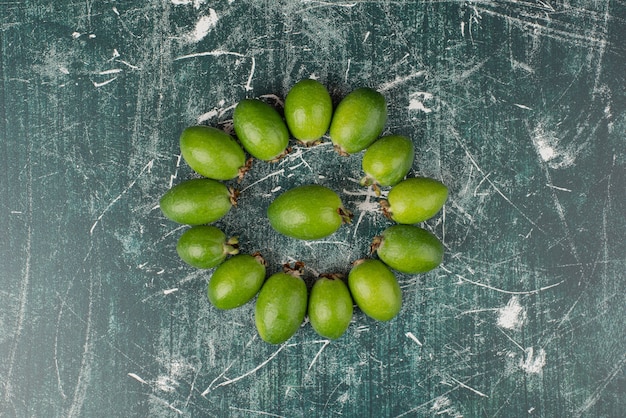 Green feijoa fruits on marble surface.