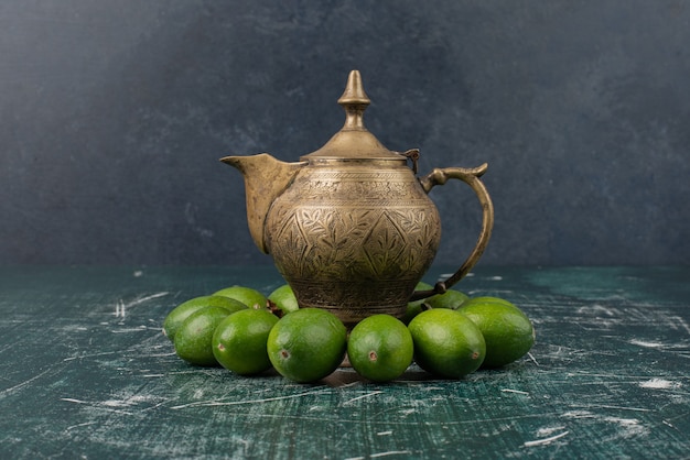 Зеленые плоды фейхоа на мраморном столе с классическим чайником
