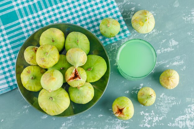 Green figs in a plate with drink flat lay on plaster and picnic cloth