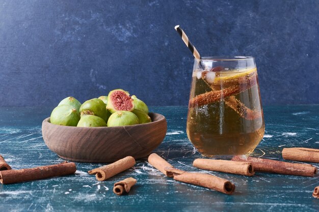 Green figs with a cup of drink on blue.